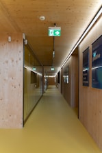 a long hallway with a green sign on the wall