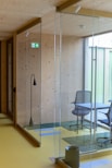 a glass walled room with a desk and chair