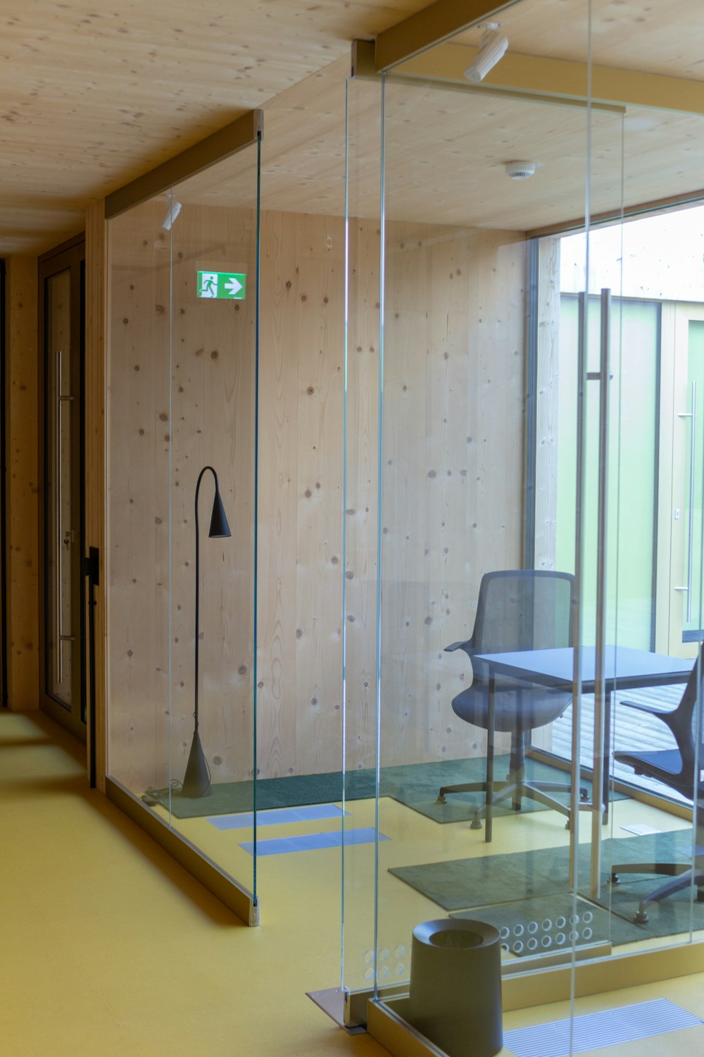 a glass walled room with a desk and chair