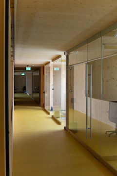 a long hallway with glass walls and a yellow floor