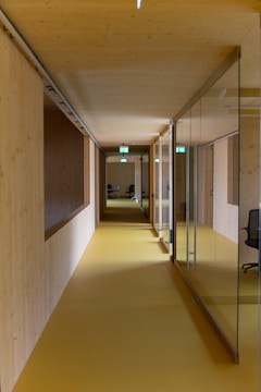 a long hallway with glass walls and a yellow floor