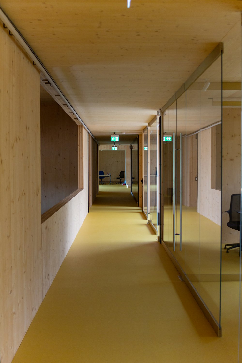 a long hallway with glass walls and a yellow floor