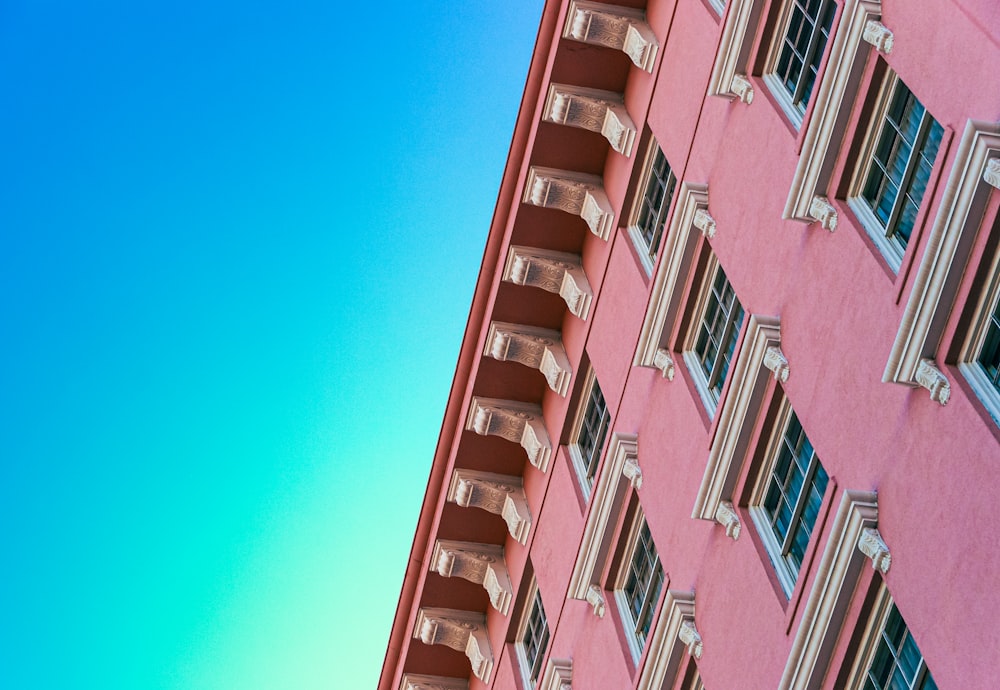 a pink building with windows and a blue sky in the background