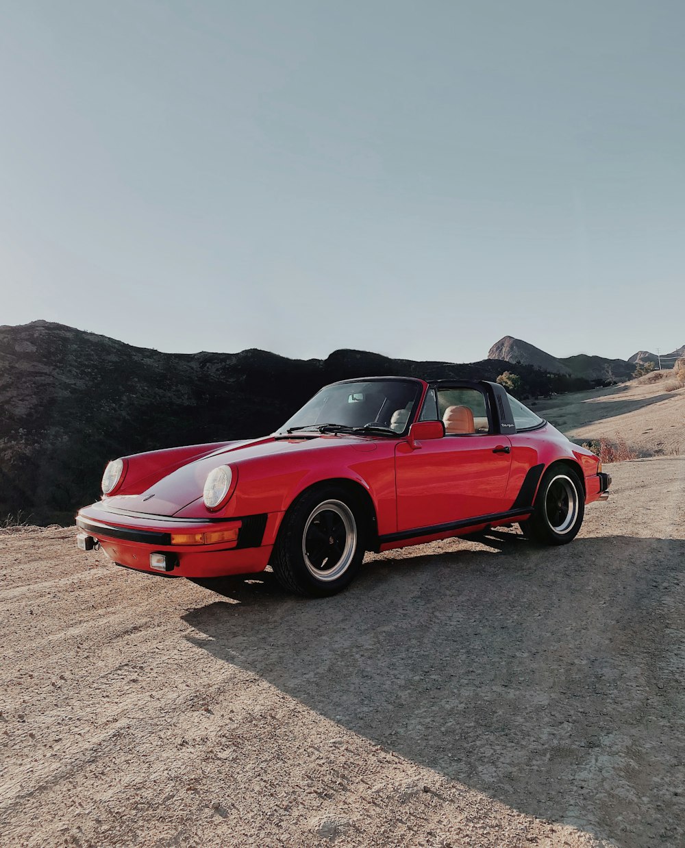 a red sports car parked on a dirt road