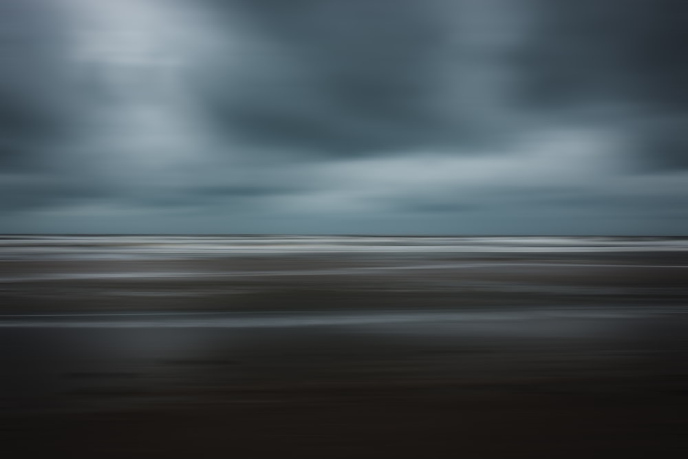 a black and white photo of a beach under a cloudy sky