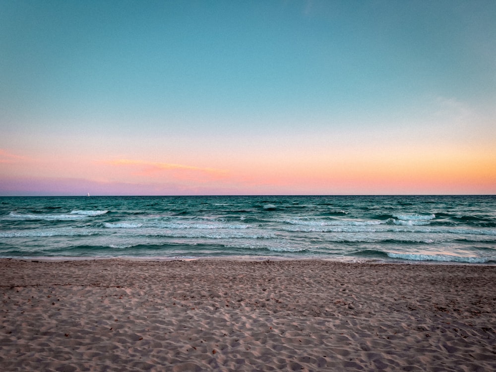 a sandy beach with waves coming in to shore