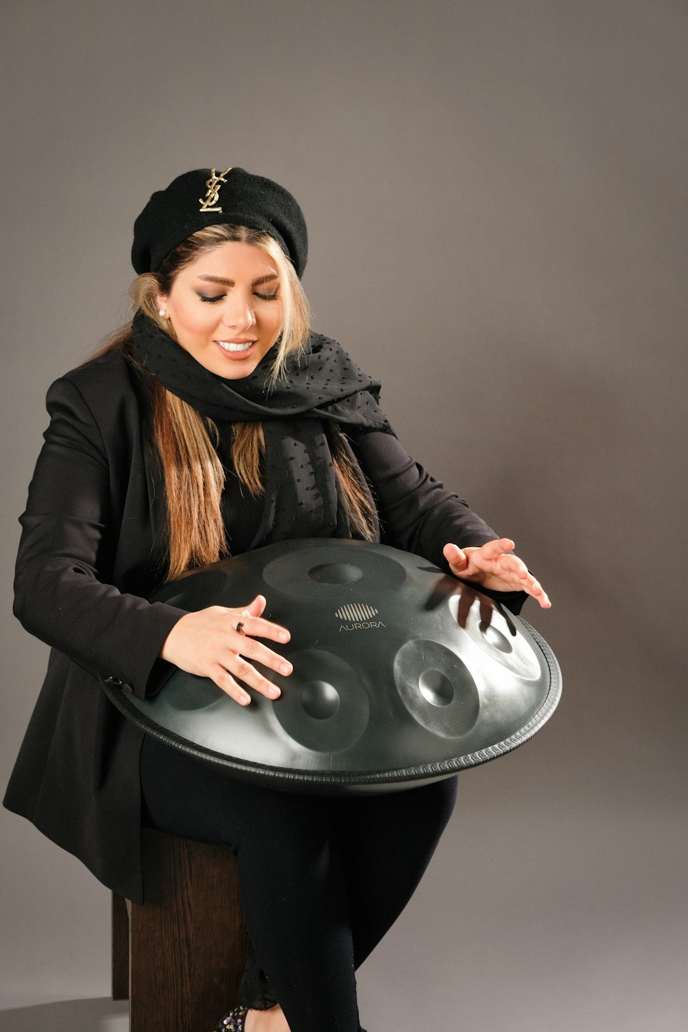 a woman in a black coat and a black hat is holding a silver platter