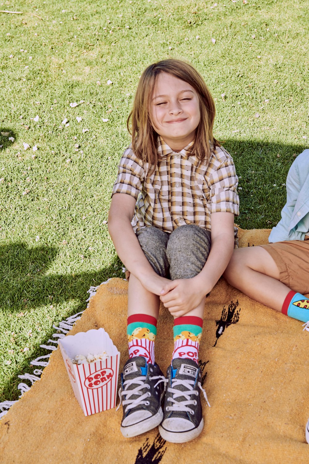 a little girl sitting on a blanket with her legs crossed