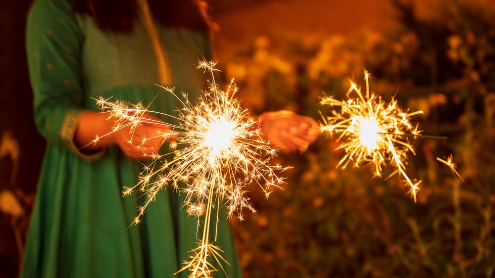 a woman in a green dress holding a sparkler