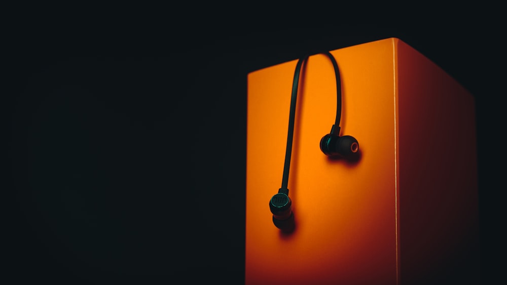 Un par de auriculares encima de una caja naranja