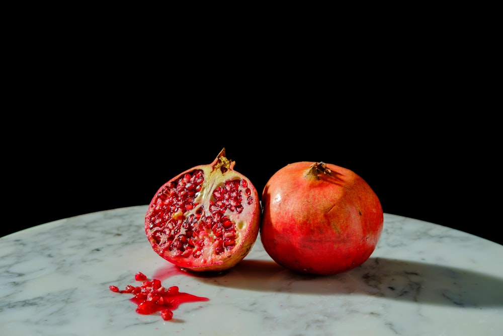 a pomegranate on a marble table with a black background