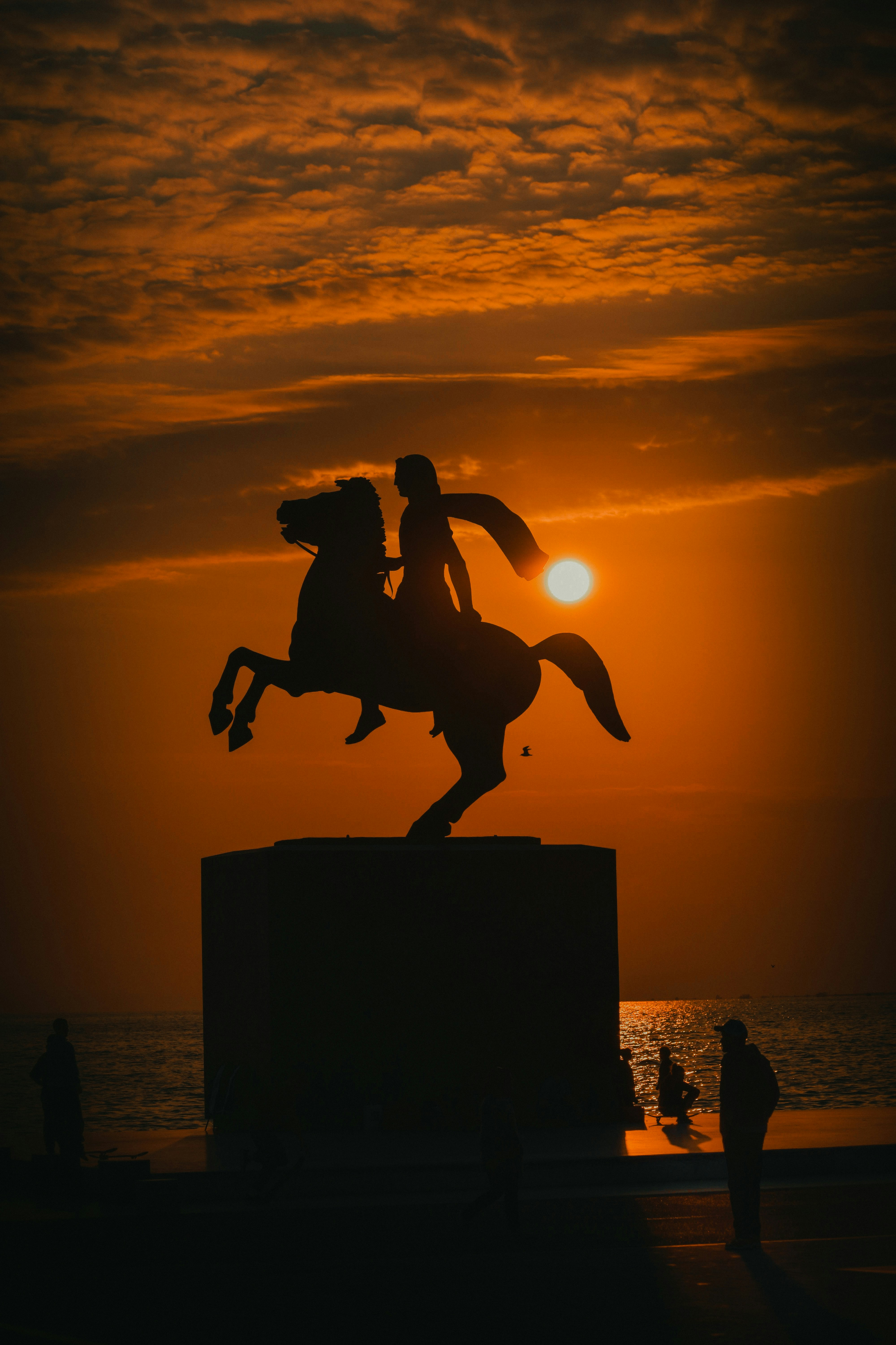 Una estatua de una persona montando a caballo al atardecer