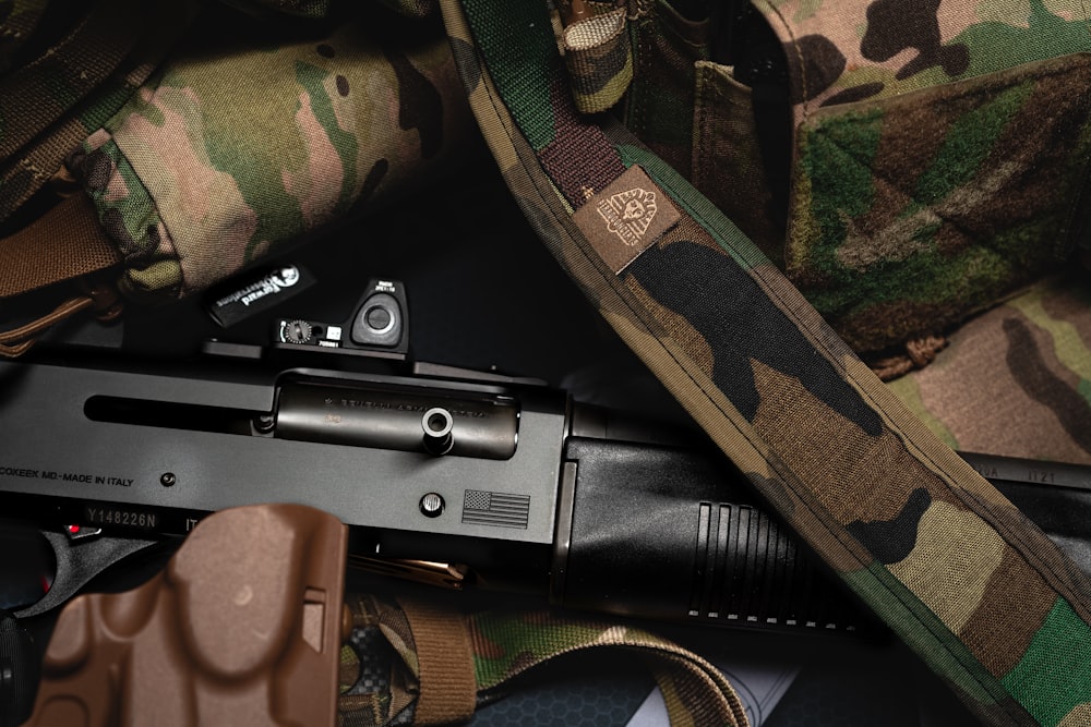 a gun laying on top of a camouflage bag