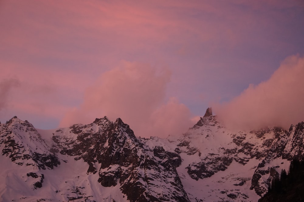 a mountain range covered in snow under a pink sky