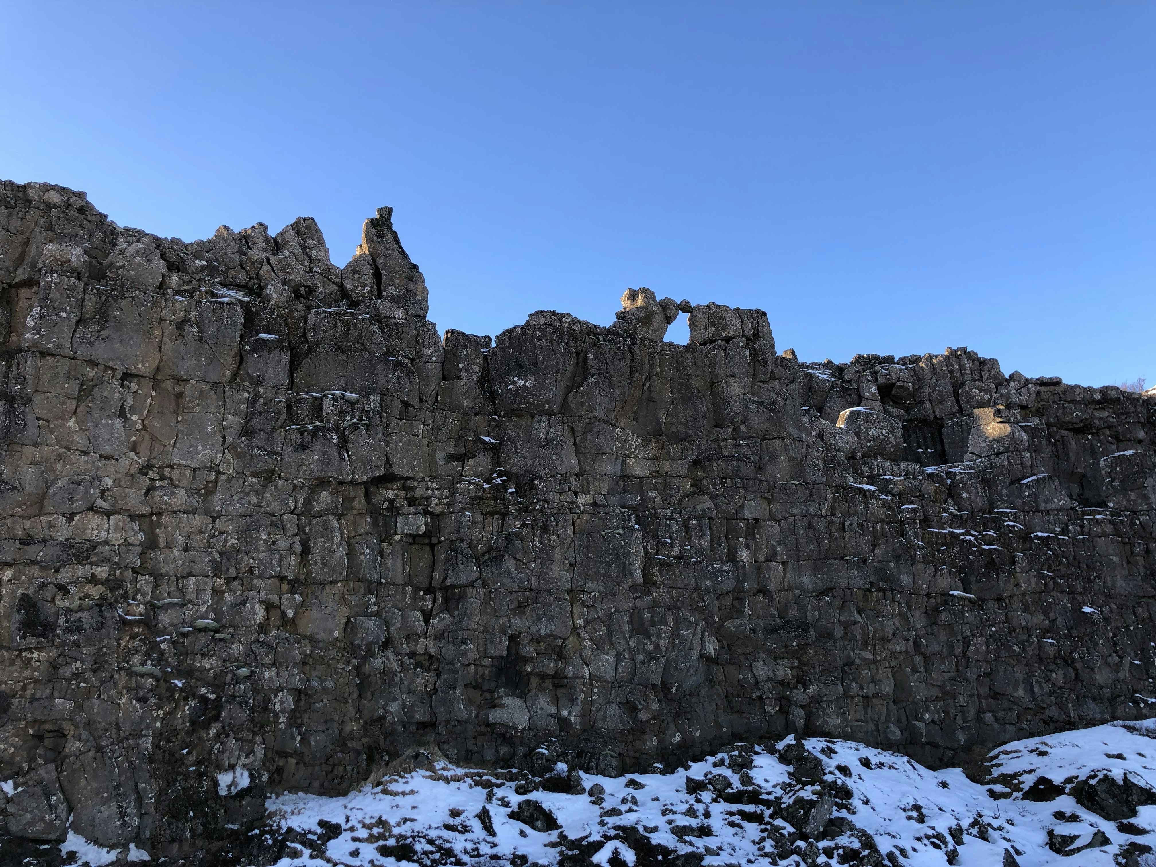 a stone wall with snow on the ground