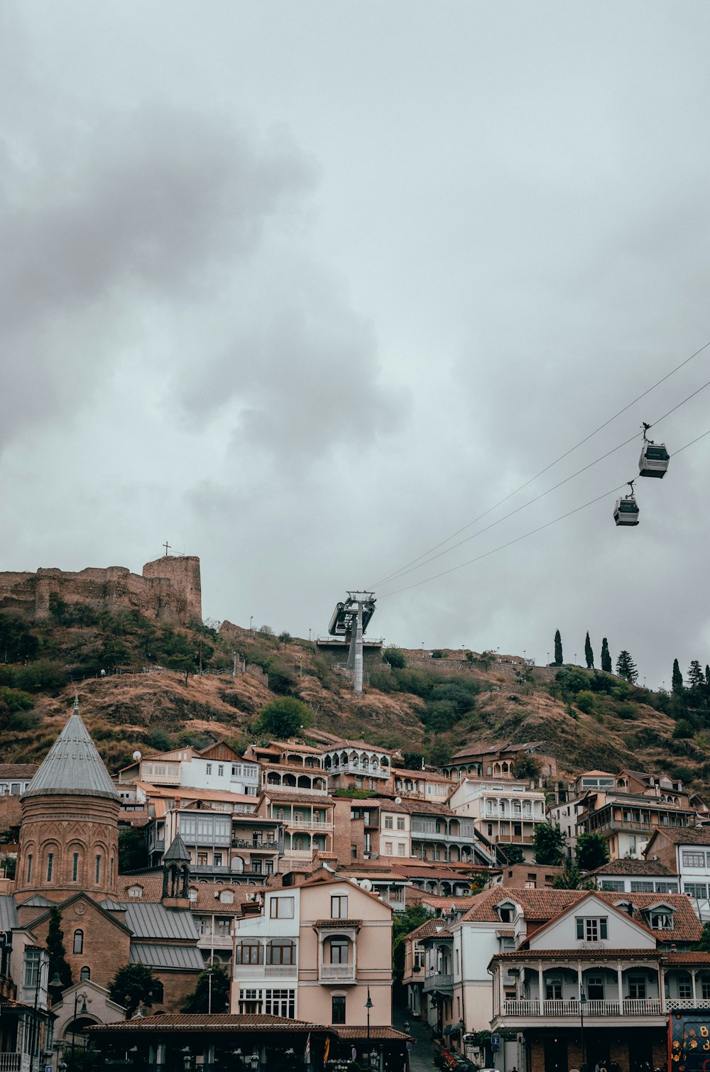 a cable car going over a city on a cloudy day