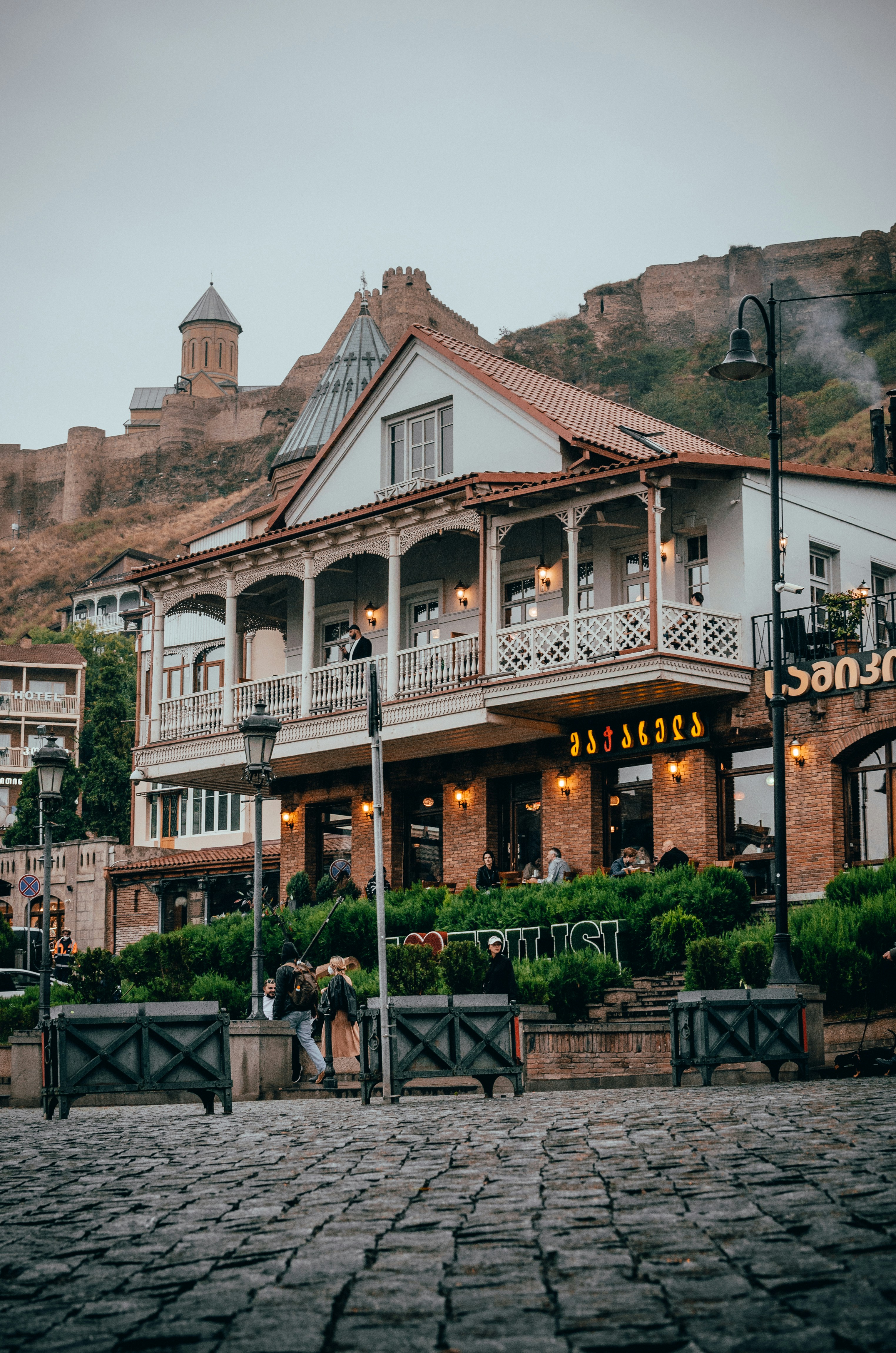 a couple of people walking past a building on a cobblestone street