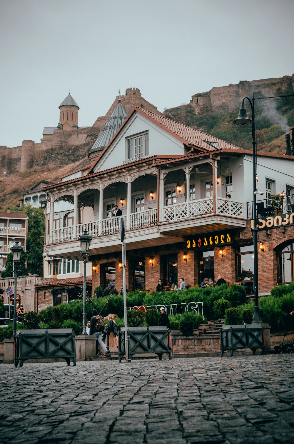 a couple of people walking past a building on a cobblestone street