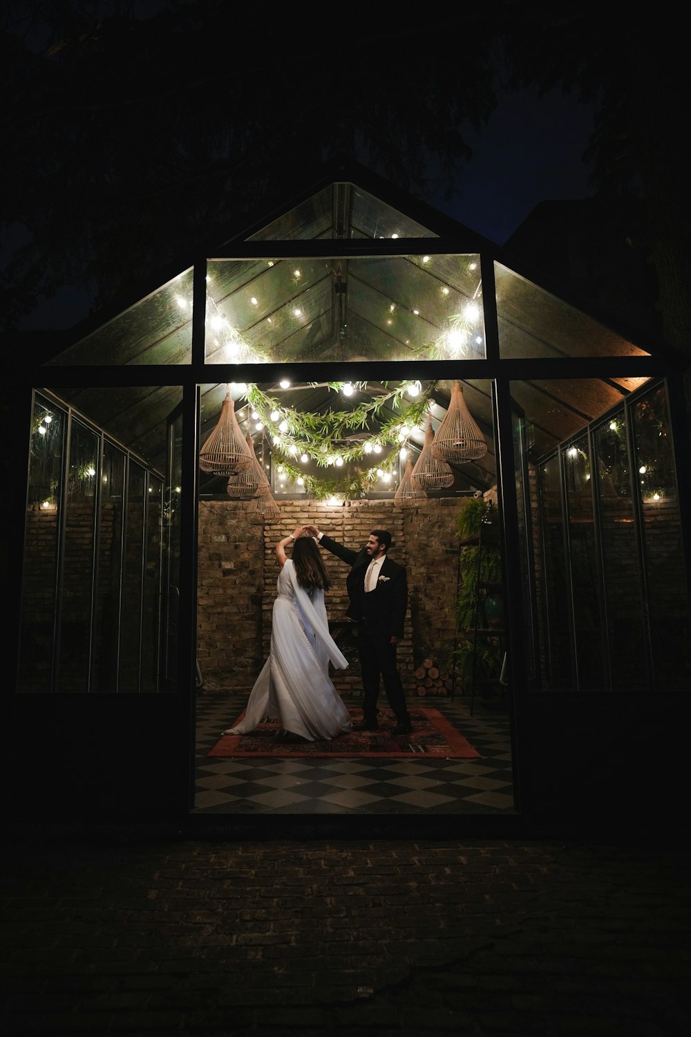 a bride and groom standing under a gazebo at night