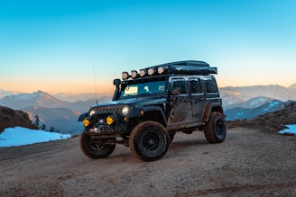 a jeep with lights on driving on a dirt road