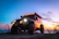 A rugged 4WD vehicle parked beside a picturesque camping spot at sunset.