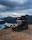 A scenic shot of the Ineos Grenadier camper parked on a rocky coastline with the rooftop tent set up.
