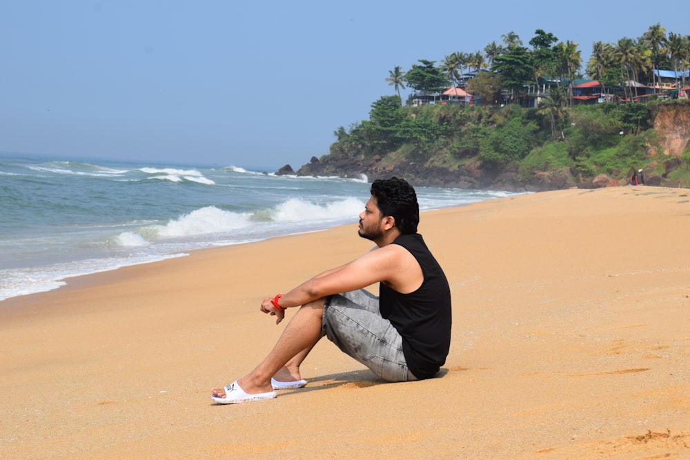 a man sitting on the beach looking out at the ocean