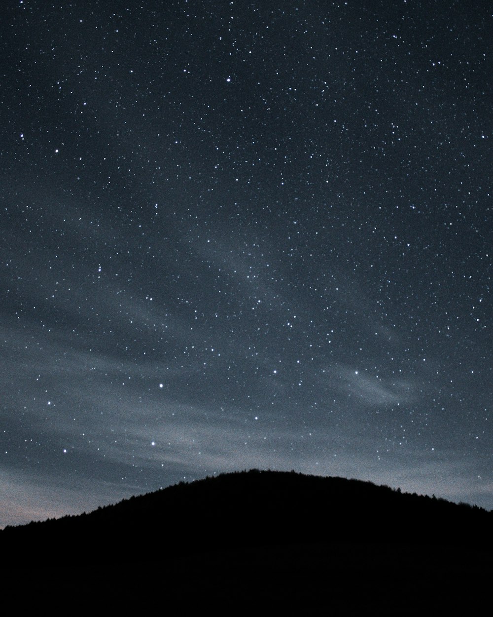 the night sky with stars above a hill