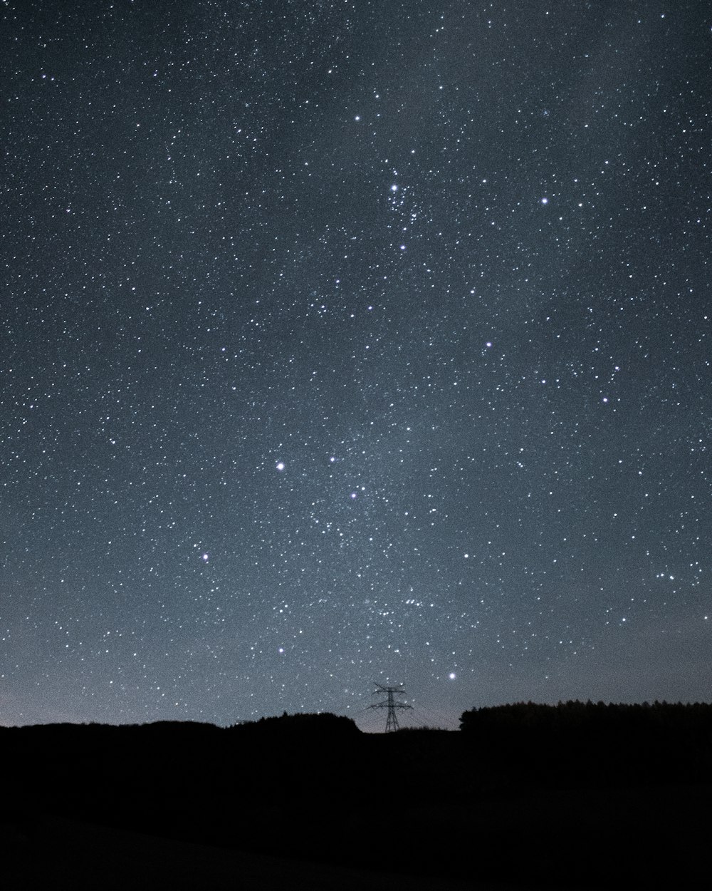the night sky with stars above a field