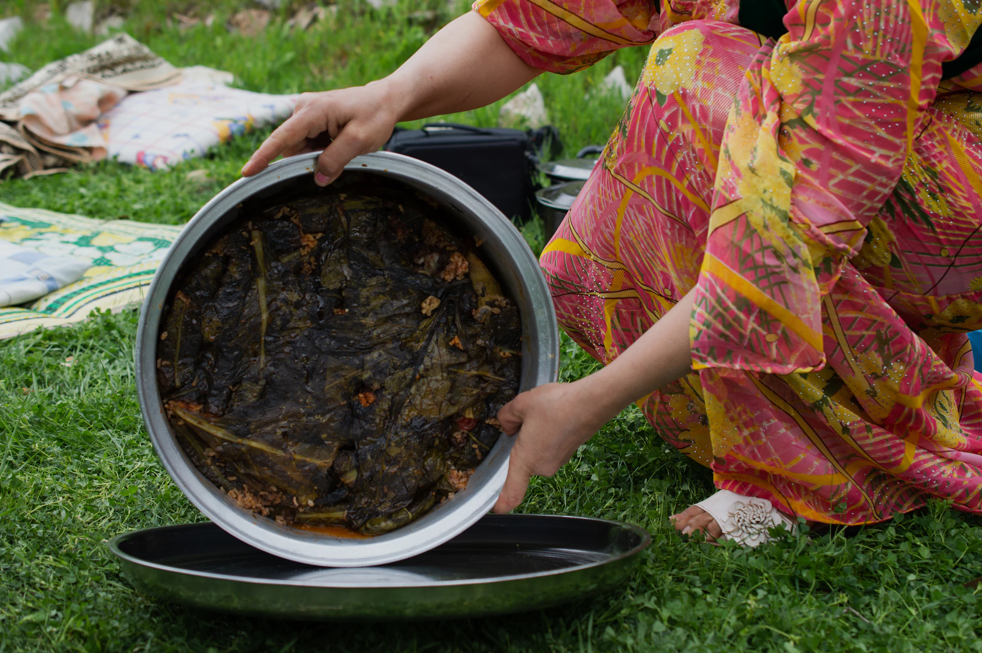 a woman in a colorful dress is holding a pan of food