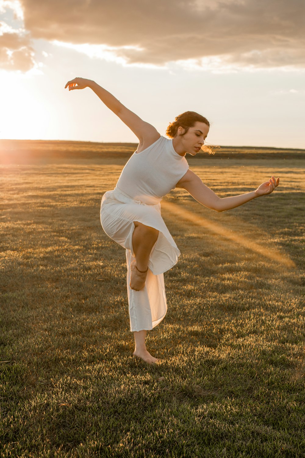 Une femme en robe blanche faisant un handstand dans un champ