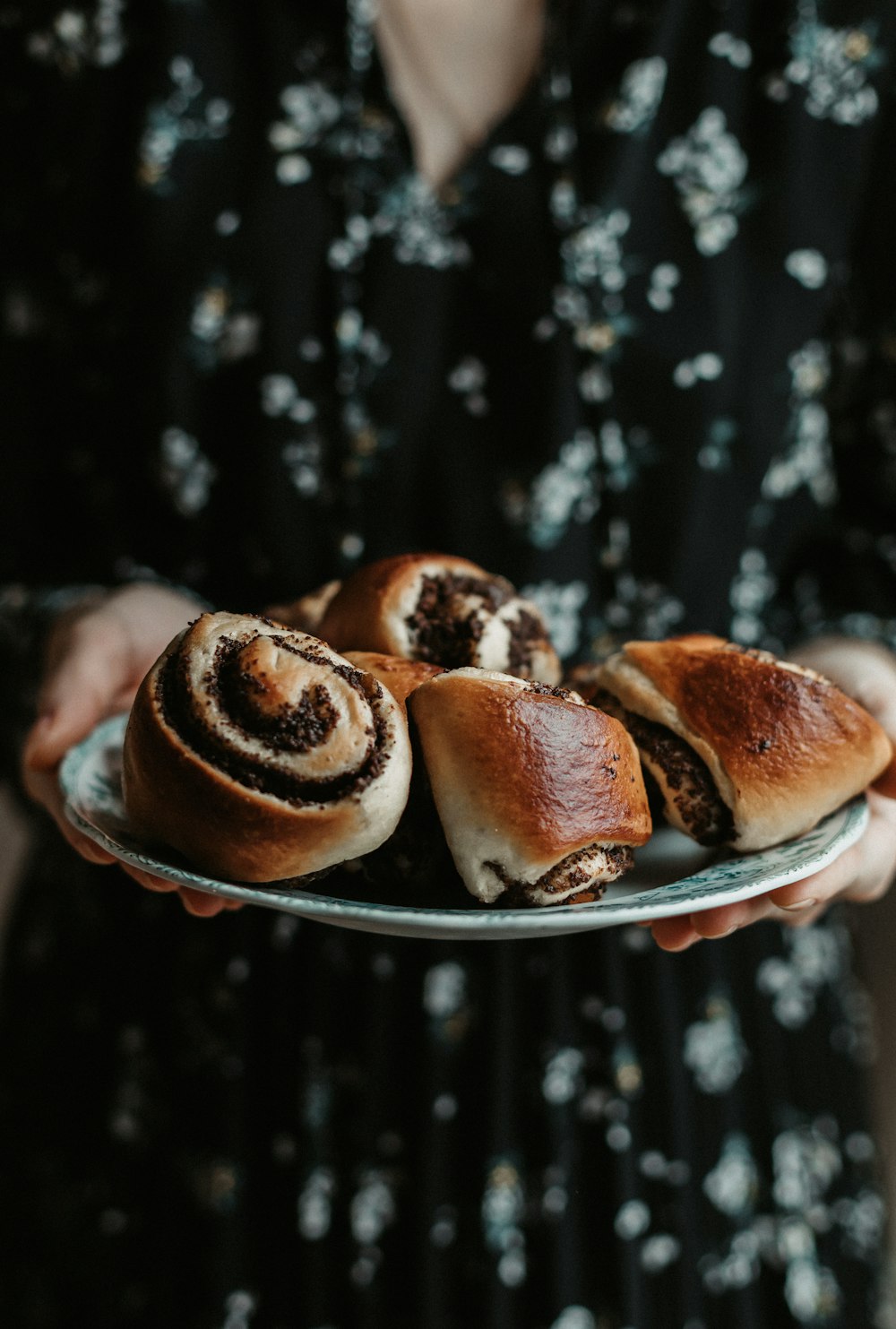 a person holding a plate with rolls on it