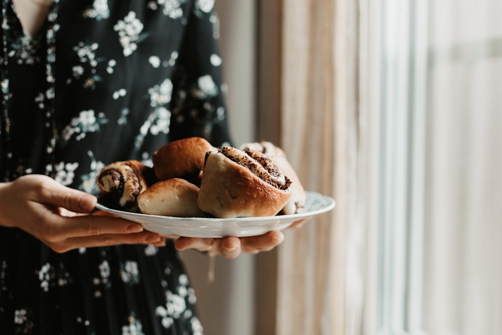 a woman holding a plate of pastries in her hands