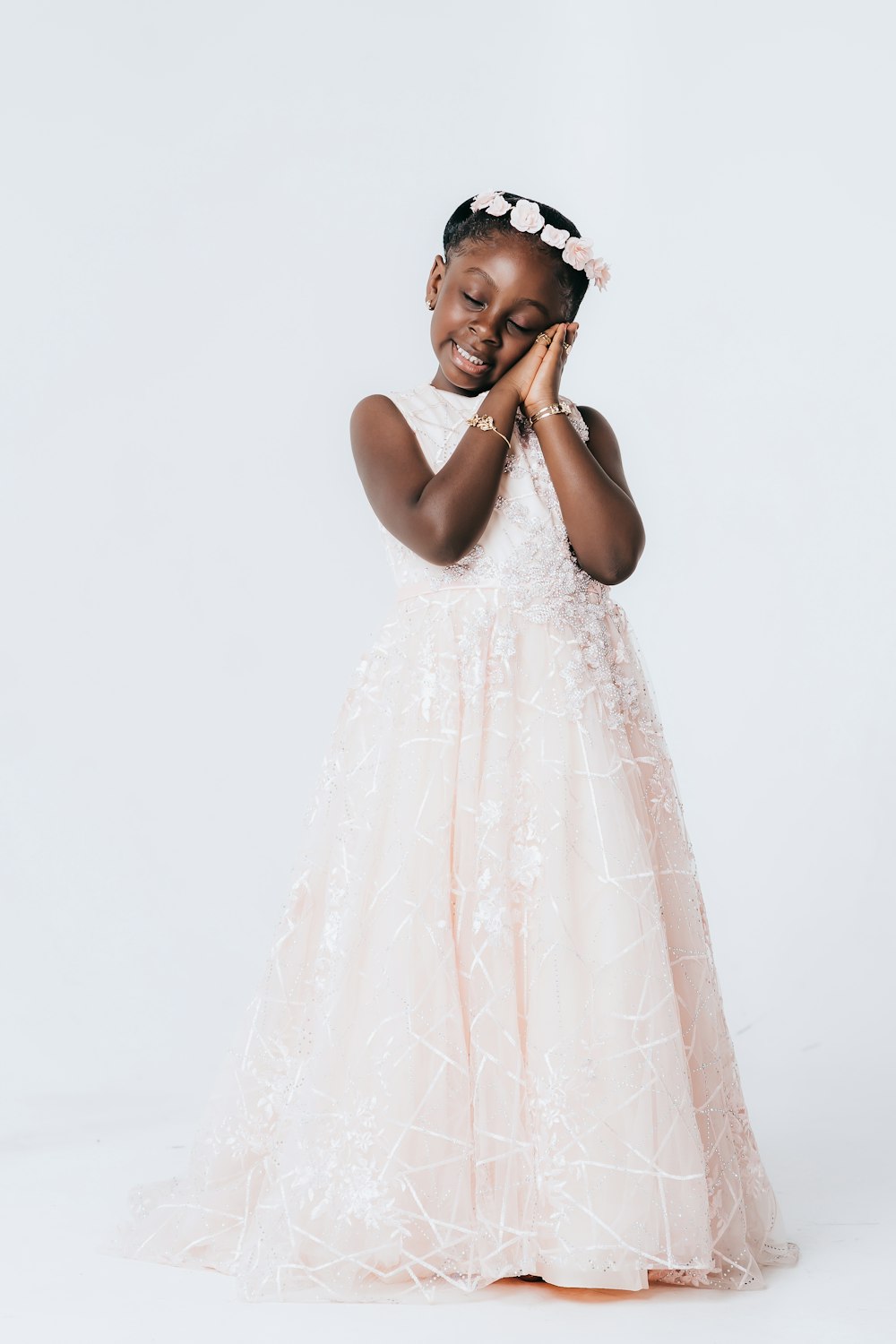 a young girl in a pink dress holding her hands together