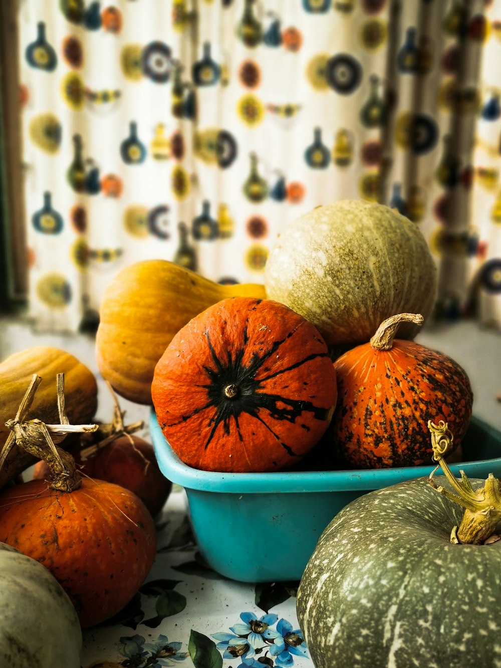 a blue bowl filled with pumpkins on top of a table