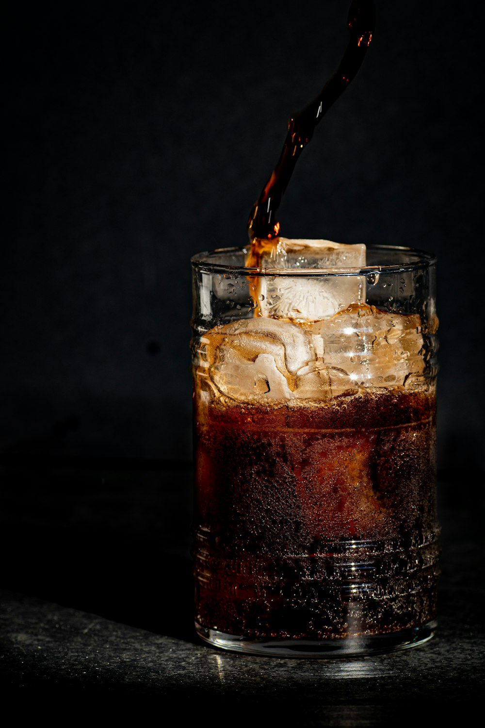 a glass filled with ice and coke on a table