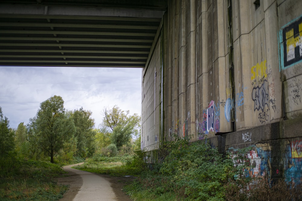 a dirt road under a bridge with graffiti on it