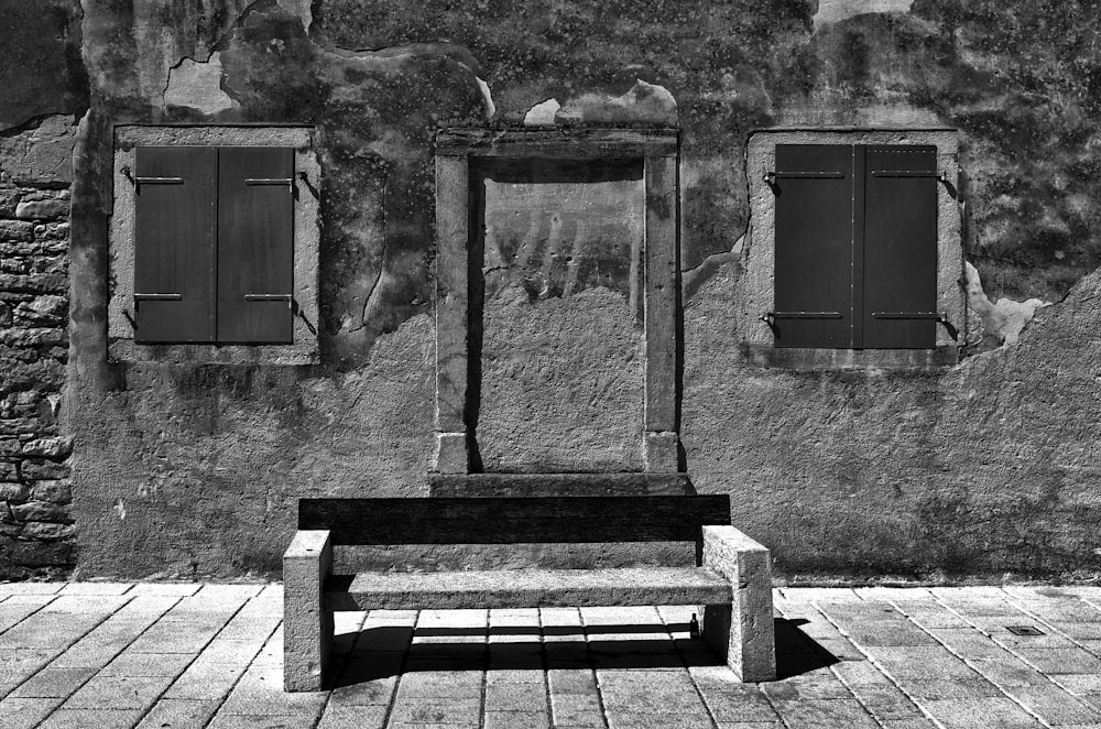 a black and white photo of a bench in front of a building