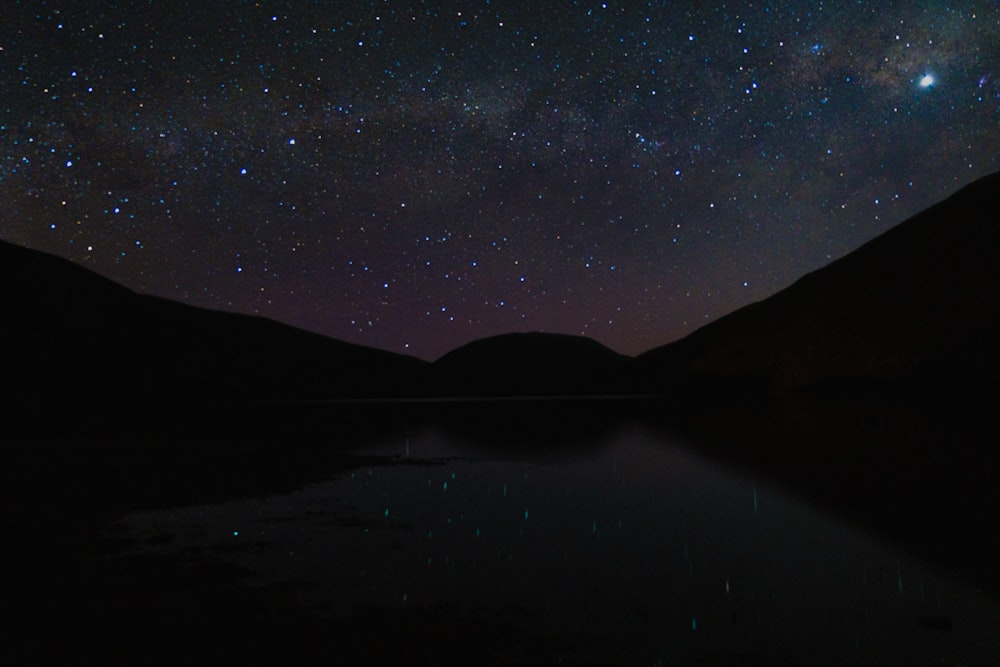 the night sky is filled with stars above a lake