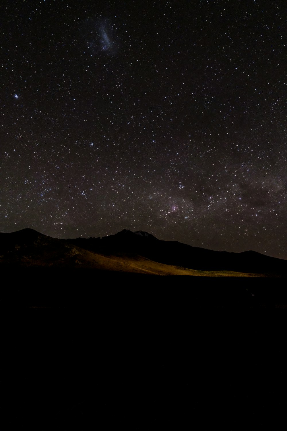 the night sky with stars above a mountain range