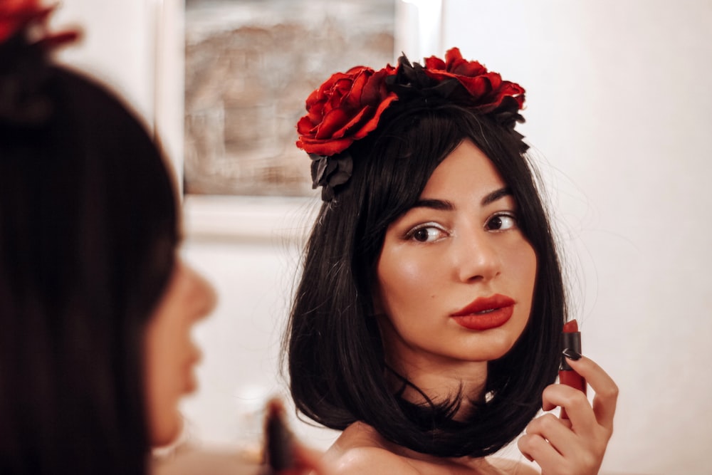 a woman is putting lipstick on her face