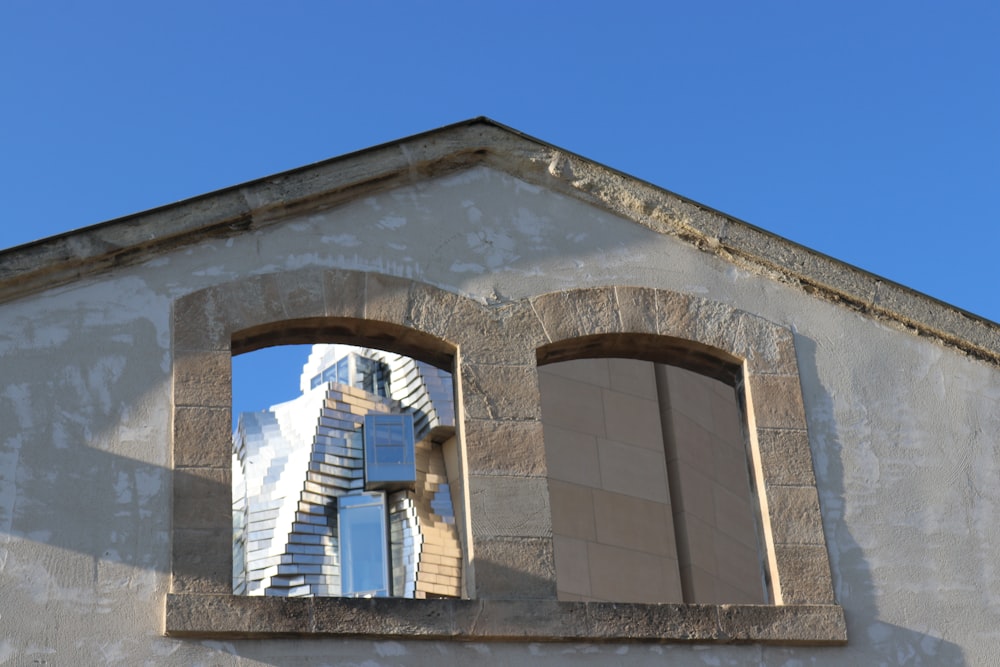 a building with a window and a ladder reflected in the window