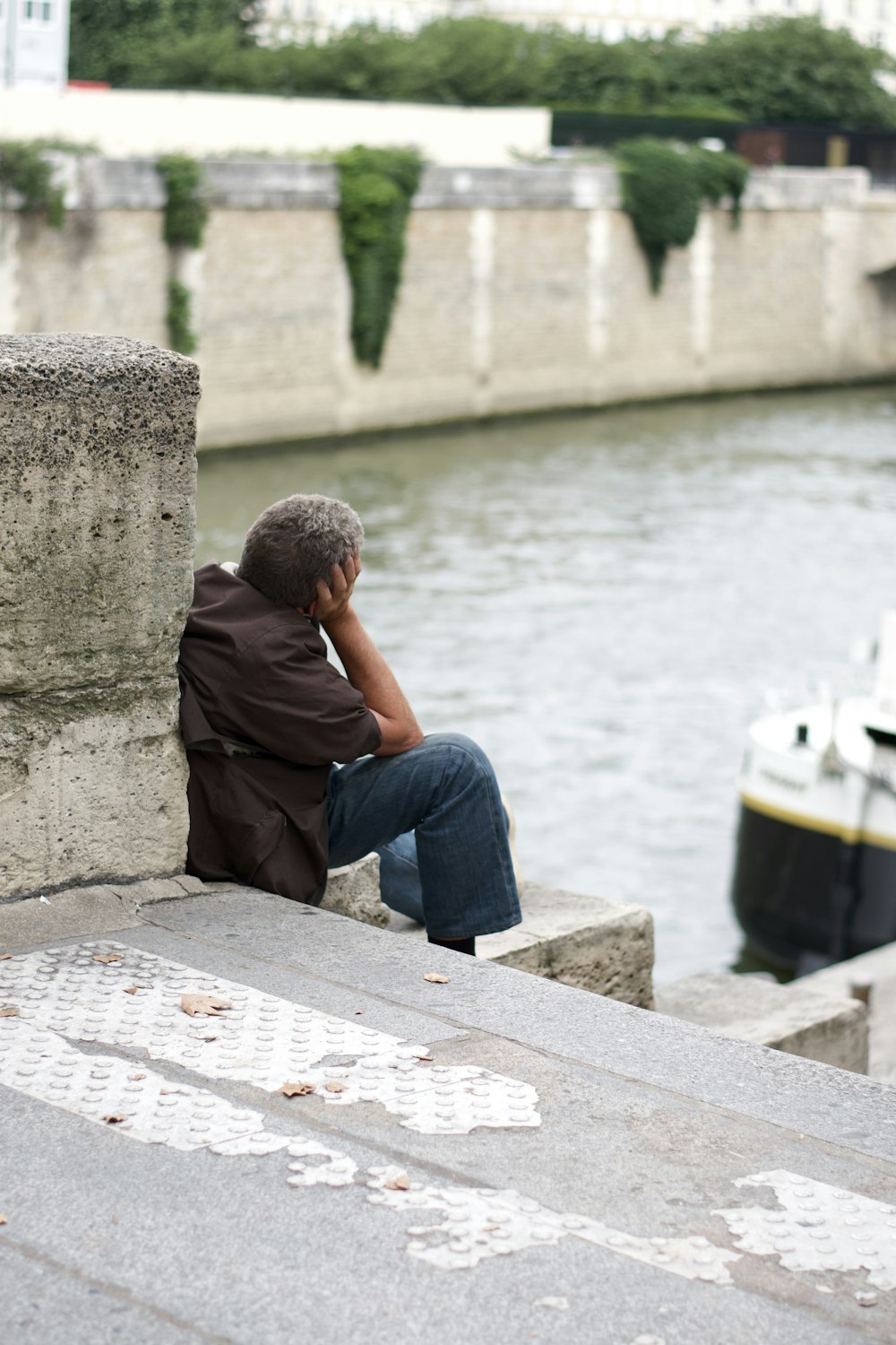 a man sitting on a ledge next to a body of water