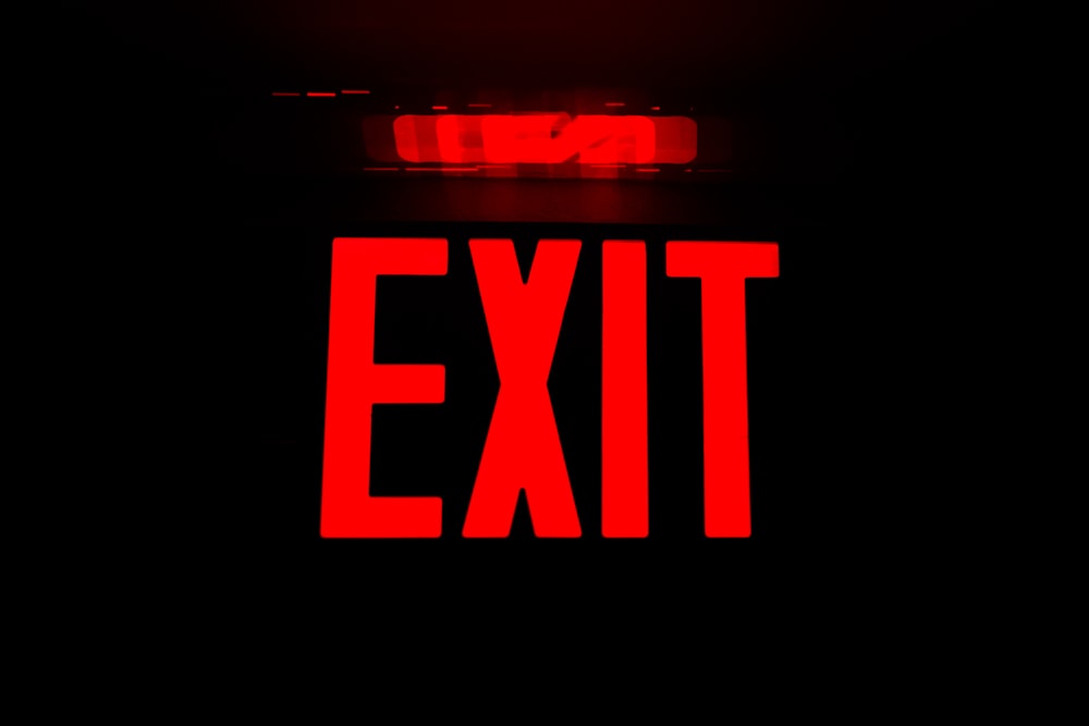 a close up of a red exit sign on a black background