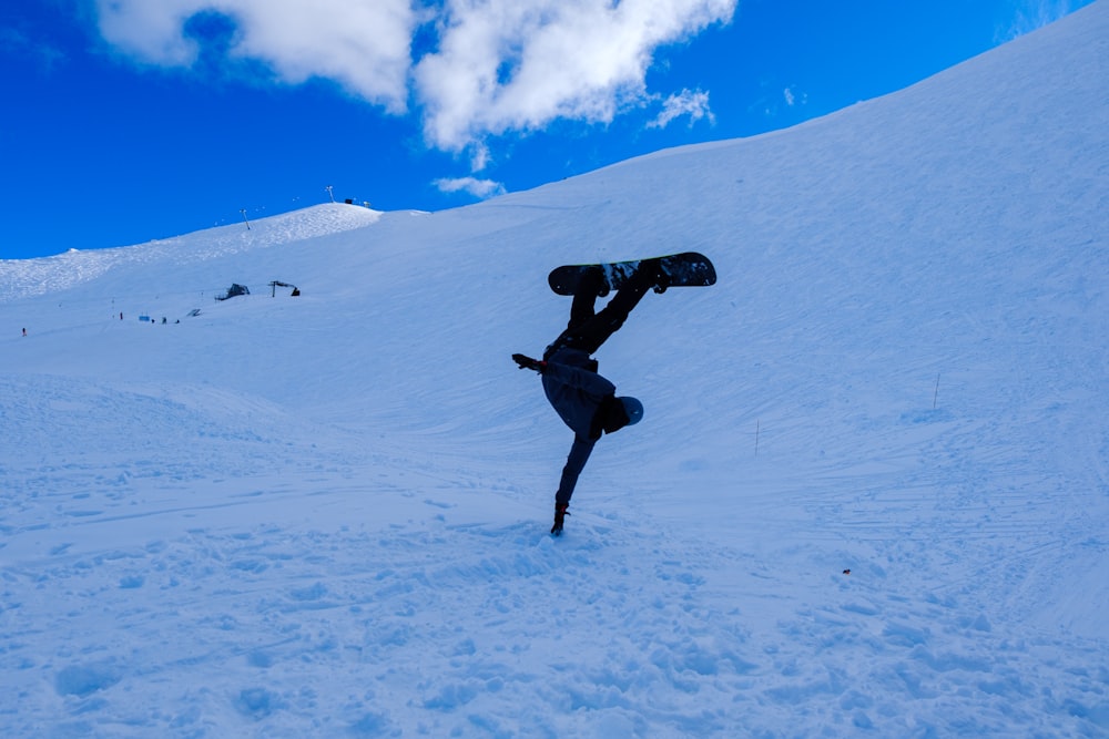 a snowboarder doing a handstand in the snow