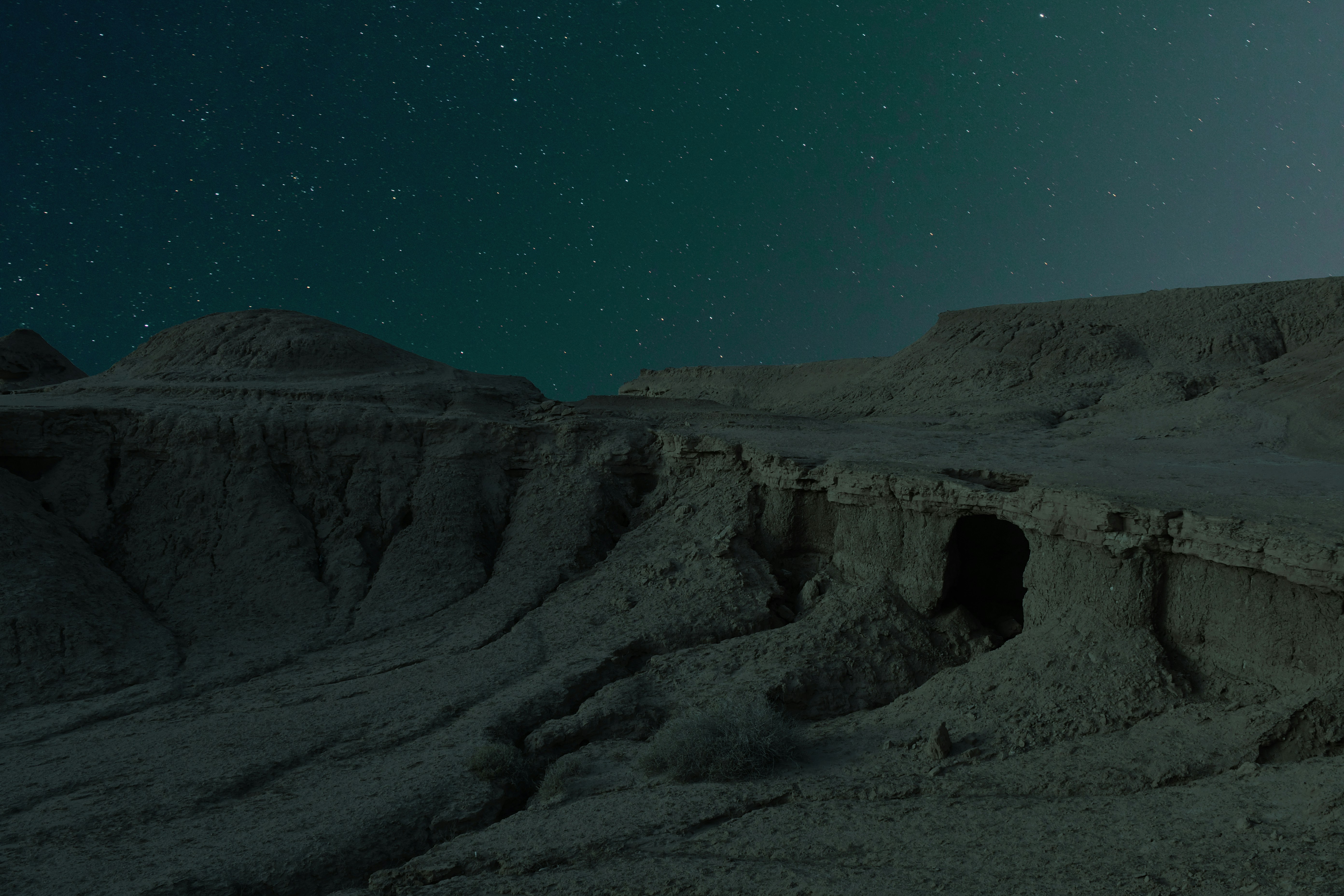 a cave in the middle of a desert under a night sky
