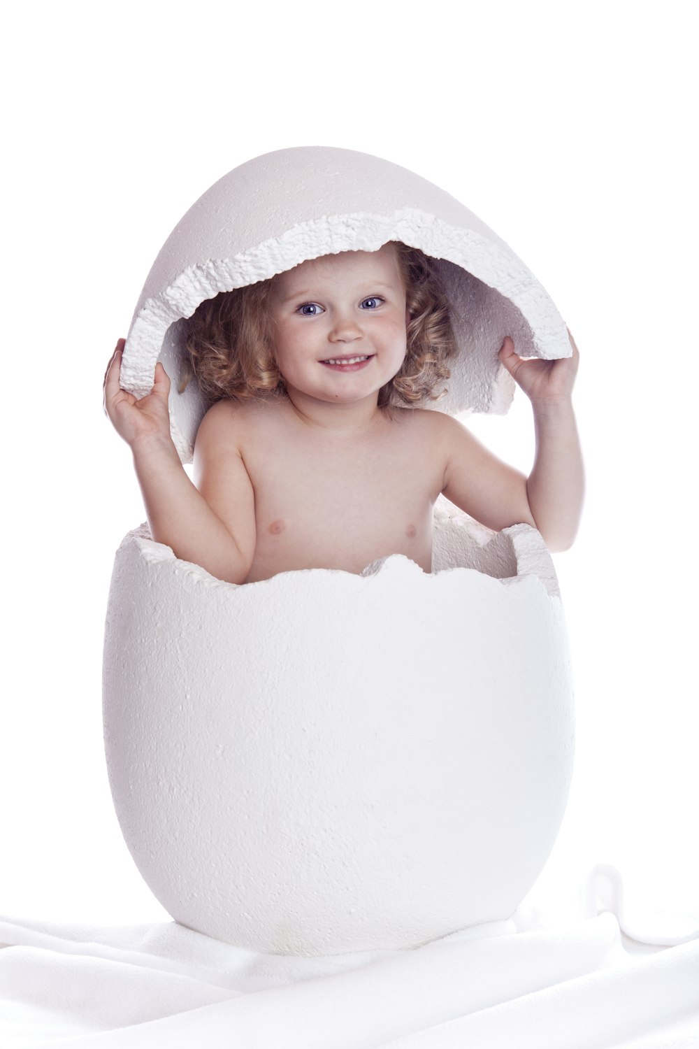 a baby in an egg shell on a white background