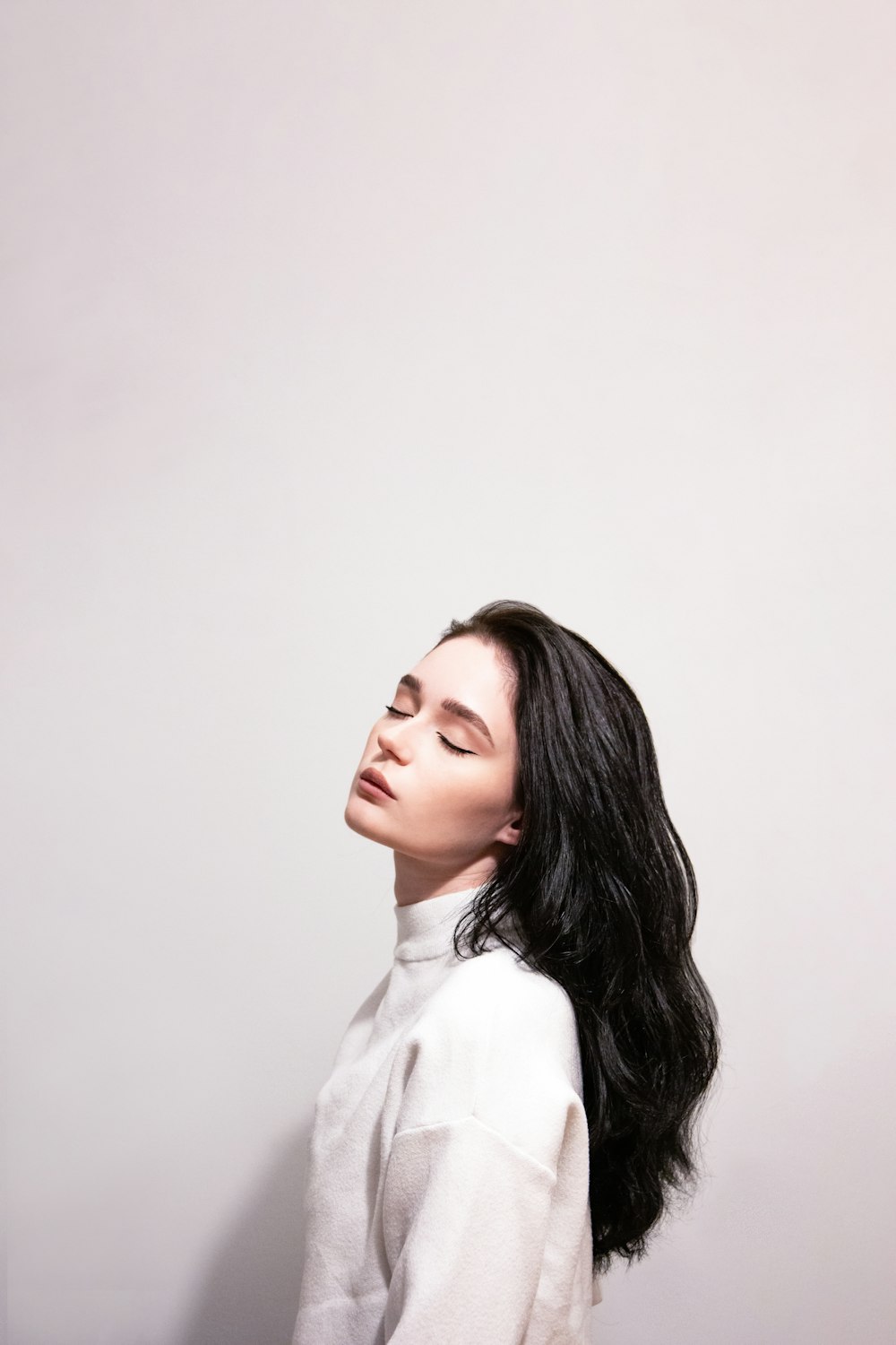 a woman with long black hair standing in front of a wall