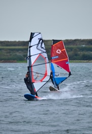 a person windsurfing in the ocean on a cloudy day