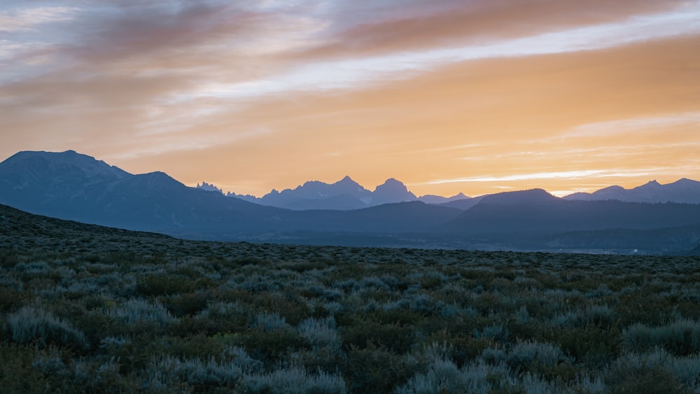 the sun is setting over the mountains in the distance